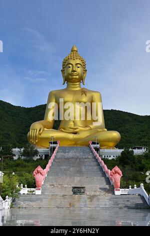 Gradini che conducono al gigantesco Buddha seduto dorato in una postura che tocca la terra o al mudra di Bhumisparsha, di fronte al monte Khao Wong Phrachan, Lopburi Foto Stock