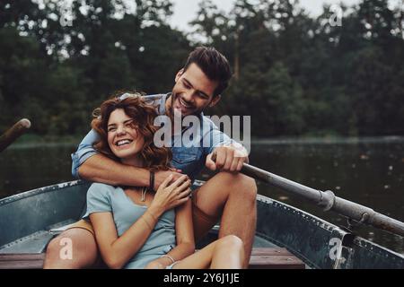 Allontanarsi da tutto. Bella giovane coppia che abbraccia e guarda lontano mentre si gode un appuntamento romantico sul lago Foto Stock