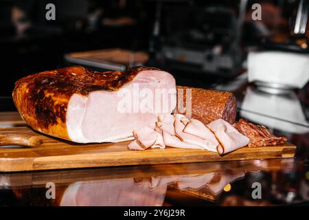 Selezione di carni gastronomiche esposte su un tavolo di legno con prosciutto, salame e prosciutto, concetto gastronomico Foto Stock