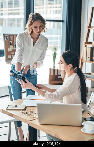 Cosa ne pensi? Belle giovani donne che guardano e toccano l'abbigliamento mentre passano del tempo in officina Foto Stock