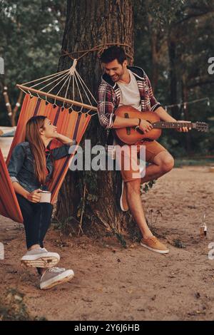 Cantare per il suo unico amore. Bel giovane che suona la chitarra per la sua bella ragazza mentre trascorri del tempo libero all'aria aperta Foto Stock