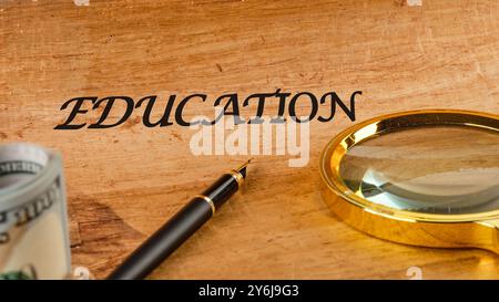 Parole EDUCATIVE sul papiro in una composizione con una penna stilografica, una lente d'ingrandimento e dollari americani Foto Stock