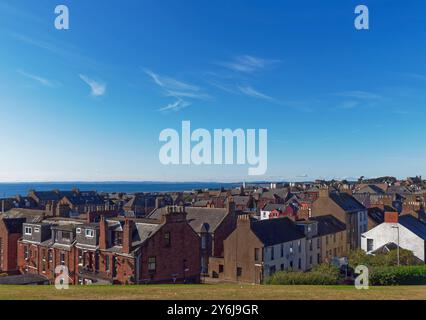 Una vista attraverso i tradizionali edifici in pietra e i tetti di Arbroath verso la costa di Fife all'incrocio tra Hill Place e Commerce Street. Foto Stock