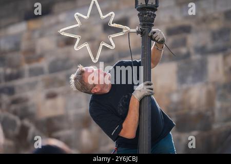 Praga Repubblica Ceca, 09192024. Un lavoratore installa una decorazione natalizia vicino al Ponte Carlo. Foto Stock
