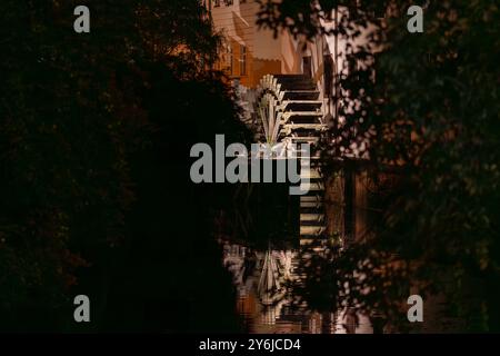 Vista della grande ruota di legno di un mulino ad acqua sul fiume Moldava nella città vecchia di Praga. Una passeggiata in città in una calda notte d'autunno senza nuvole. Foto Stock