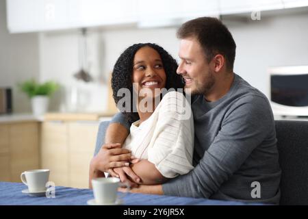 Felice coppia interrazziale che si guardano in amore in cucina a casa Foto Stock