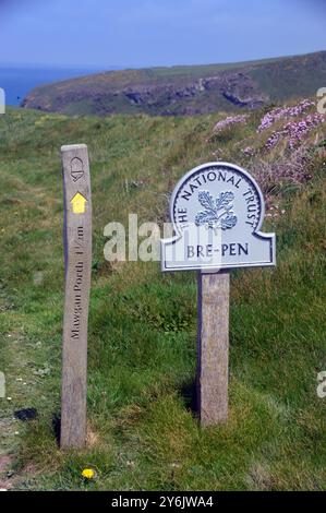 Il cartello del National Trust per Bre-Pen e il cartello in legno per Mawgan Porth sul sentiero sul sentiero costiero sud-occidentale, Cornovaglia settentrionale, Inghilterra, Regno Unito. Foto Stock