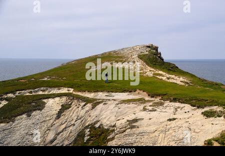 Man (escursionista) Walking on Path to Trevelgue Head on Porth Island a Porth Bay vicino Newquay sul Southwest Coastal Path, North Cornwall, Inghilterra, Regno Unito Foto Stock