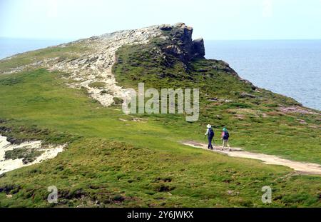 Coppia (escursionisti) camminando sul sentiero per Trevelgue Head a Porth Island, vicino a Newqusay, sul sentiero costiero sud-occidentale, Cornovaglia settentrionale, Inghilterra, Regno Unito Foto Stock