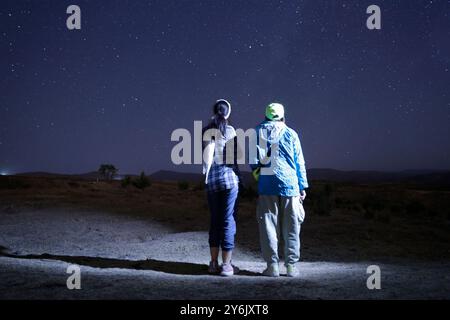 Due persone che guardano le stelle sotto un cielo notturno limpido in un luogo remoto. Foto Stock