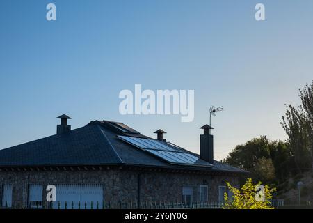 vista di una grande casa a conduzione familiare moderna con pannelli solari a energia sostenibile. Sta nascendo con un cielo blu e alberi verdi. Concetto di energia solare Foto Stock