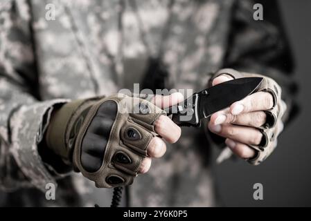 L'uomo che indossa guanti tattici usando un coltello pieghevole. Foto Stock