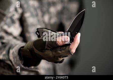 L'uomo che indossa guanti tattici usando un coltello pieghevole. Foto Stock