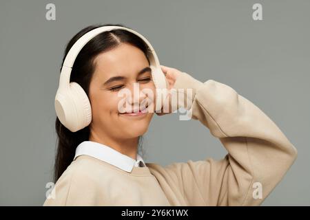 Una giovane donna sperimenta la beatitudine mentre ama le sue canzoni preferite in un abbigliamento alla moda. Foto Stock