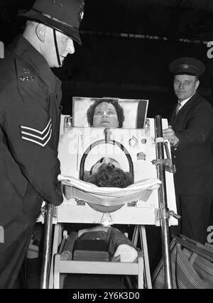 Iron Lung Girl inizia nuova vita Un poliziotto aiuta nello scarico del polio contenente la ragazza della poliomielite Margaret Dixon alla stazione di Euston Margaret è stata in un polmone di ferro per dieci anni per vivere nel Sussex marzo 1960 Foto Stock