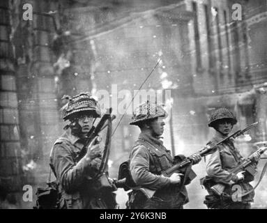 Belfast . Irlanda del Nord . Con un edificio sparato dai rivoltosi che bruciano sullo sfondo le truppe britanniche stanno di guardia nella zona di Catholic Falls Road di questa città lacerata dalla rivolta. Le truppe britanniche marciarono in città dopo una notte di violenza in cui quattro persone erano morte. 15 agosto 1969 Foto Stock