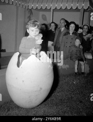 Londra : giusto per ricordarvi che la Pasqua non è lontana, John Harper di 4 anni, di Clapham (Londra), raffigurato in un ambiente stagionale. Nessuno alla Easter Farm di un Oxford Street Store dice se fosse John o la ragazza che è stata schiusa da questo uovo gigante. 27 marzo 1953 Foto Stock