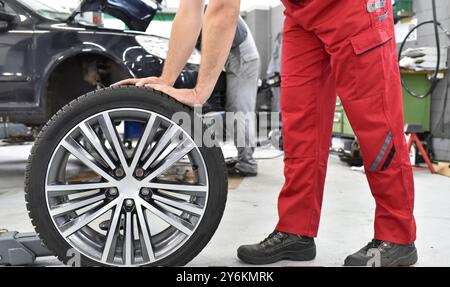 La sostituzione di un pneumatico nel corso di un workshop - assembler in abiti da lavoro Foto Stock