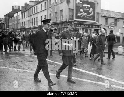 Londonderry: Irlanda del Nord: Un membro della Royal Ulster Constabulary accompagnato da un poliziotto militare, di pattuglia nell'area di Bogside di questa città oggi, quando la polizia dell'Irlanda del Nord è entrata nell'area cattolica romana per la prima volta da agosto, quando i cattolici hanno lanciato rocce e missili attraverso barricate contro la polizia e i protestanti. 17 ottobre 1969 Foto Stock