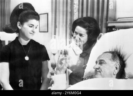 Bethesda Naval Hospital, Washington: Il presidente degli Stati Uniti Lyndon B. Johnson dà il segno "O.K." a questa moglie, la signora Claudia "Lady Bird" Johnson (centro) e alla figlia luci Baines Johnson dopo che è stato operato con successo oggi, 16 novembre, per la rimozione di un polipo non canceroso nella gola e la correzione di un'ernia addominale. Al Presidente, che ha 58 anni, dovrebbe essere permesso di alzarsi dal letto e camminare nell'immediato futuro. 16 novembre 1966 Foto Stock