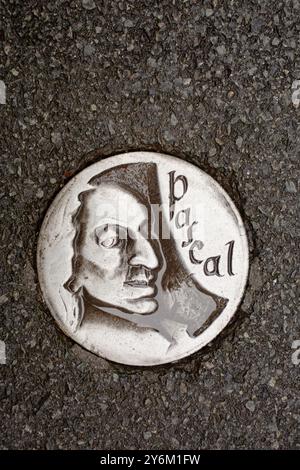 Francia, Clermont-Ferrand, 63, effigie metalliche di Blaise Pascal incastonate in asfalto stradale. Foto Stock