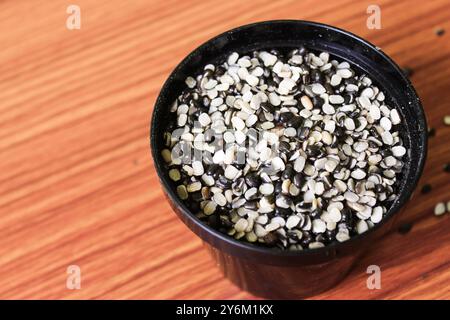 Split Black Lentil conosciuto anche come Black Gram, Black Urad dal, Vigna Mungo, Urad Bean su fondo in legno marrone Foto Stock