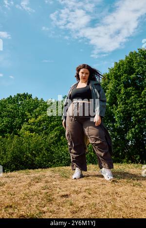 Una donna allegra e grande si crogiola al sole, abbracciando la fiducia in un campo verde lussureggiante. Foto Stock