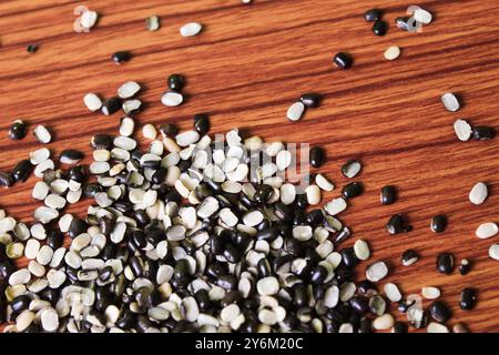 Split Black Lentil conosciuto anche come Black Gram, Black Urad dal, Vigna Mungo, Urad Bean su fondo in legno marrone Foto Stock