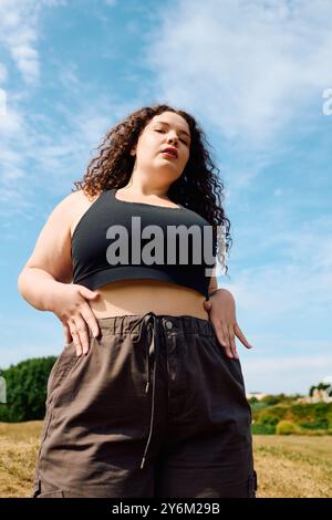 Una donna sicura di sé si trova in una splendida posizione in mezzo a un tranquillo paesaggio naturale. Foto Stock