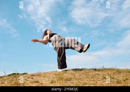 Una donna allegra e di grandi dimensioni gode di un momento di libertà in un campo soleggiato, ballando con grazia. Foto Stock