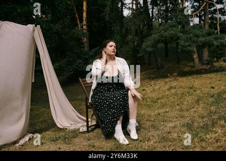 Una bella donna di grandi dimensioni siede graziosamente nella natura, abbracciando la calma bellezza del momento. Foto Stock