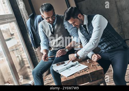 Alla ricerca di una musa alla moda. Bel giovane che sceglie il design con il suo cliente mentre trascorre del tempo in officina Foto Stock