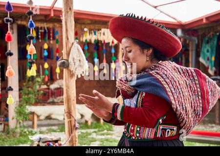 Un abile artigiano di Chinchero viene catturato tessendo tessuti vivaci. La scena riflette il ricco patrimonio culturale, mostrando abiti tradizionali e. Foto Stock