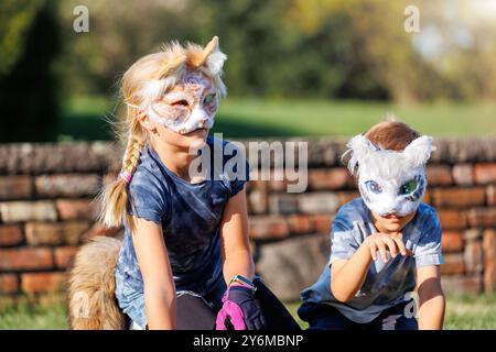 La giovane bambina indossa la maschera pelosa del gatto divertiti a giocare all'aperto nel parco di Forest Street. I bambini hanno un carattere di animali selvatici alla moda Foto Stock