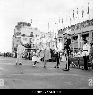 Aeroporto di Entebbe, Uganda: Un po' di Ugandian nel suo miglior "vestito da festa" lancia un corteccio e presenta un bouquet di fiori alla duchessa H.R.H. di Kent quando è arrivata qui con H.R.H. Duke of Kent (centro, testa inclinata in avanti) il 7 ottobre. Il duca e la sua duchessa (l'ex Miss Katherine Worsley) sono attualmente in Uganda in rappresentanza di H.M. Queen alle Independence Celebrations. 9 ottobre 1962 Foto Stock