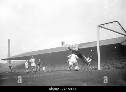 Il portiere del Real Madrid Juan Alonso salta via un tiro dal Manchester United all'interno del destro Bill Whelan (camicia scura) durante la partita di andata e ritorno della Coppa dei campioni di ieri sera. Il risultato fu un pareggio per 2-2, dando al Real Madrid un totale vincente di 5-3. 26 aprile 1957 Foto Stock