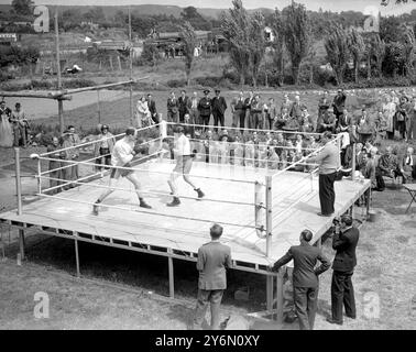 Visitatori del Barley Mow di Betchworth, Surrey. Aiuta a portare qualcosa dell'atmosfera di White City ai quartieri di allenamento di Freddie Mills lì oggi (lunedì) mentre Mills (indossando la guardia del capo) si allena con Leeds Boxer al Robinson sul ring all'aperto. Mills, campione mondiale dei pesi massimi leggeri, sta ora mettendo il tocco finale al suo allenamento per la sua lotta contro il campione britannico, Empire ed europeo dei pesi massimi Bruce Woodcock al White City Stadium (Londra il 2 giugno). I titoli di Woodcock saranno in gioco. Tra gli spettatori della falesia di Barley oggi c'erano ex militari disabili dell'Hospita di St. Mary Foto Stock