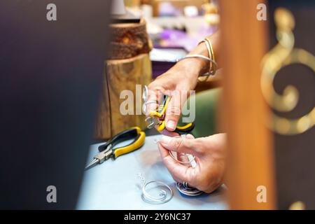 Donna ispanica irriconoscibile che realizza orecchini negli anni '50 sul suo stallo di strada e vende gioielli in filo di alluminio fatti a mano Foto Stock