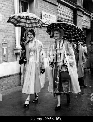 Ombrelli e impermeabili proteggono gli abiti indossati dalla signora McKinley Clark e dalla figlia in arrivo per l'inaugurazione del Royal Ascot Race Meeting 16 giugno 1953 Foto Stock