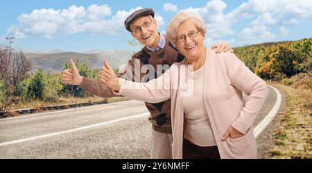 Una coppia di anziani allegri che fanno autostop su una strada Foto Stock