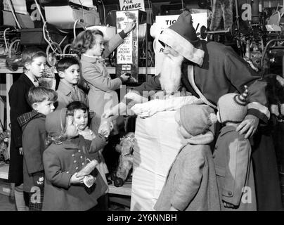 Il Babbo Natale in un grande magazzino di Brixton (South London) non sporca mai le mani con articoli terreni come le monete. Quindi, perché il negozio non vada in perdita, è stata installata una macchina per il cambio di moneta per i bambini che li assiste nell'acquisto di regali, distribuiti da Babbo Natale. Qui la 9enne Violet Staunton di Stockwell a Londra inserisce mezza corona (2/6d o 12,5p) nella macchina prima di fare qualche parola con il vecchio gentiluomo barbuto. - 8 dicembre 1960 Foto Stock