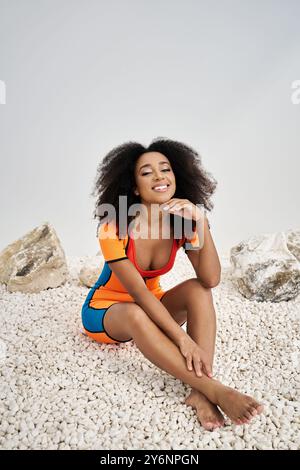 Una giovane donna con bellissimi ricci gode un momento di tranquillità, sorridendo dolcemente mentre è seduta. Foto Stock