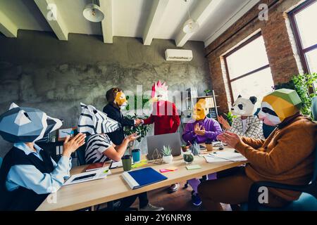 Foto di panda gorilla bradipo zebra procione maschera uomini d'affari che applaudono leone gallo stretta di mano loft ufficio interno Foto Stock