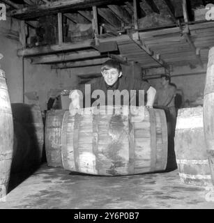 Lo Smithfield Market, nato a Londra, Liverpudlian Alan Rudkin, campione britannico dei pesi gallo, crede nel "Rolling Out the Barrel" al lavoro. L'enorme barile contiene pelli per salsicce. - 2 settembre 1965 Foto Stock