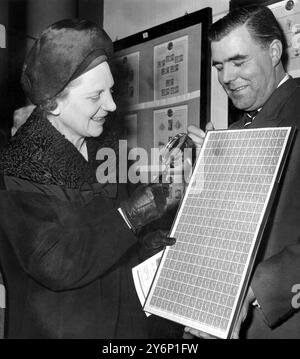 Con una lente d'ingrandimento, Miss Mervyn Pike, Assistente Postmaster generale esamina un foglio di francobolli britannici erroneamente perforati a Stampex, la National Stamp Exhibition che ha aperto alla Central Hall, Westminster, Londra 1962 Foto Stock