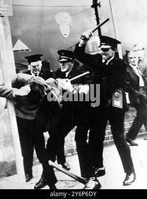 Tre poliziotti che maneggiano bastoni si avvicinano ai manifestanti a Londonderry il 6 ottobre 1968 durante violenti scontri tra manifestanti e polizia. La rivolta iniziò sabato quando i manifestanti chiesero cambiamenti nel sistema elettorale e protestarono contro la discriminazione religiosa. Ulteriori manifestazioni sono scoppiate domenica per protestare contro la presunta brutalità della polizia nei disturbi del sabato. 7 ottobre 1968 Foto Stock