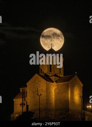 La luna piena sul monastero Tabor della trasformazione a Tbilisi, Georgia, crea una scena notturna drammatica. Foto Stock