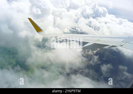 Volo sul lago di Skadar in Montenegro: Vista dalla finestra dell'ala dell'aeroplano e delle nuvole, con la terra e il lago visibili negli spazi vuoti tra di loro Foto Stock