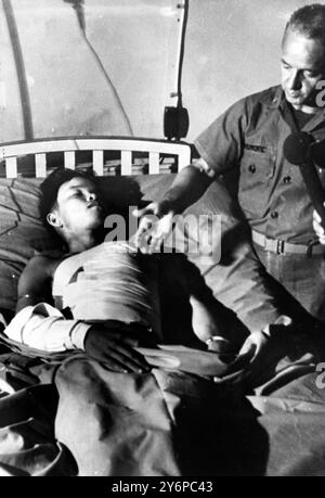 La foto radiofonica ricevuta oggi mostra il soldato dell'esercito vietnamita, Nguyen Van Long (22), che riposa in un ospedale dell'esercito americano, con il suo fianco bendato, come medico dell'esercito americano, Harry Dinshore racconta ai giornalisti come ha rimosso un mortaio vivo da 60 mm dal lato del primo . Long è stato colpito dal mortaio durante un' operazione . Il medico ha rimosso il guscio vivo da dietro i sacchi di sabbia , la seconda volta che un'operazione di questo calibro è stata eseguita in Vietnam . 3 ottobre 1966 Foto Stock