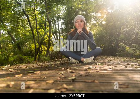 Donna sportiva seduta su una passerella riposante dopo l'esercizio fisico all'aperto, in autunno e in autunno Foto Stock